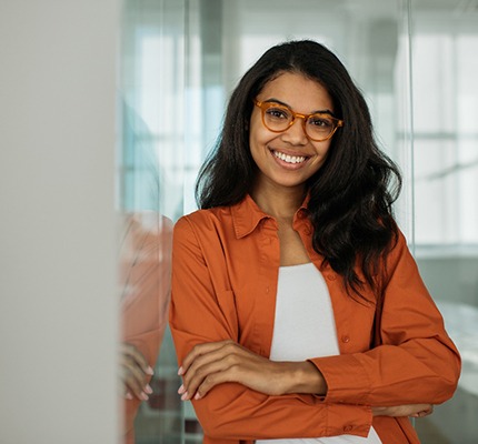 a smiling woman resting against a wall