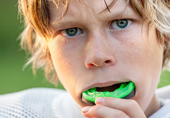 Teen boy placing green mouthguard