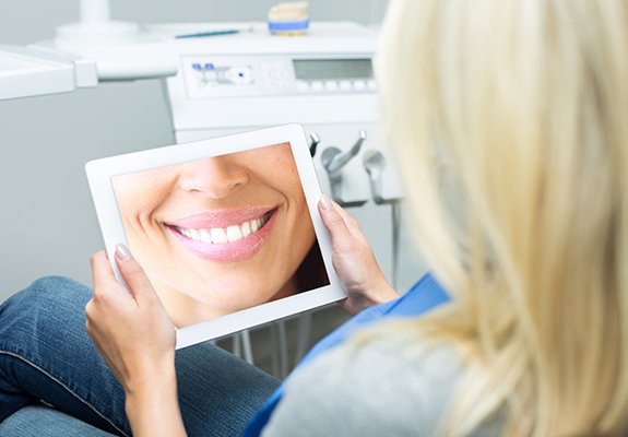 Woman looking at her smile design on tablet computer screen