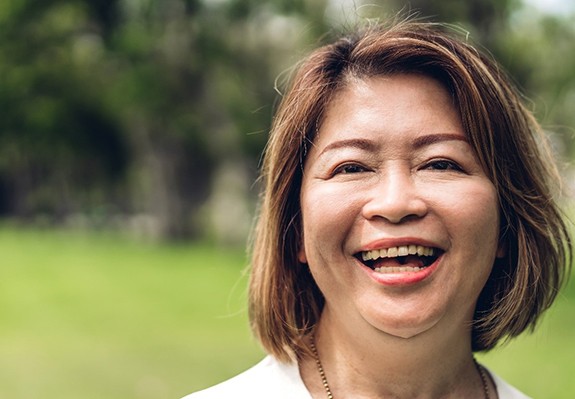 person walking through a park and smiling