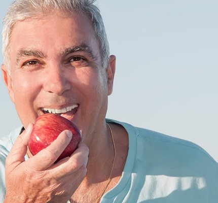an older man with dentures eating an apples