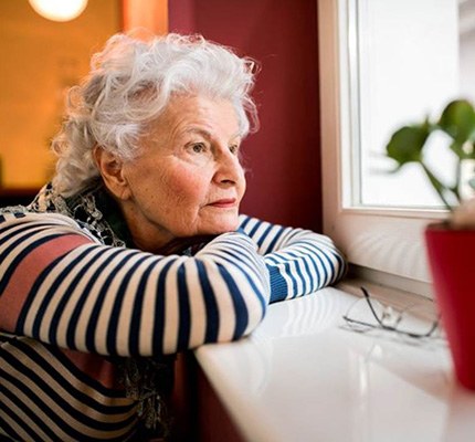 Sad senior woman looking out the window