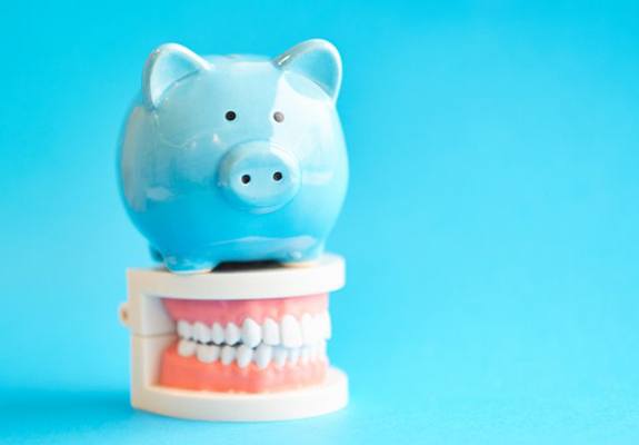 blue piggy bank sitting on top of a set of dentures