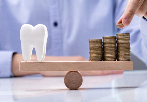 Man balancing tooth a coins on wooden scale