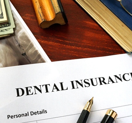 Dental insurance paperwork and pen on wooden desk