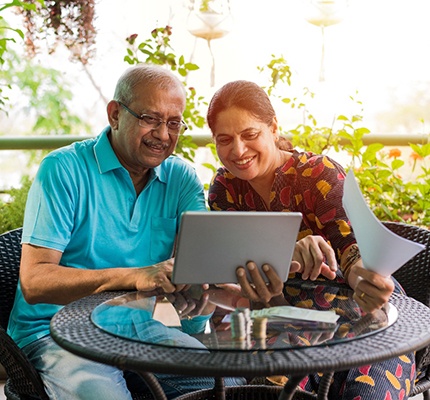 An older couple talking to someone on a tablet while outside on the patio