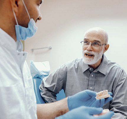 An older gentleman listens to his dentist discuss the benefits of dental implants in Fanwood