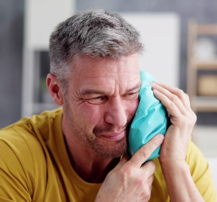 a man holding an ice pack on his cheek