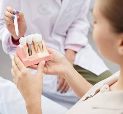 A dentist showing a patient a dental implant model