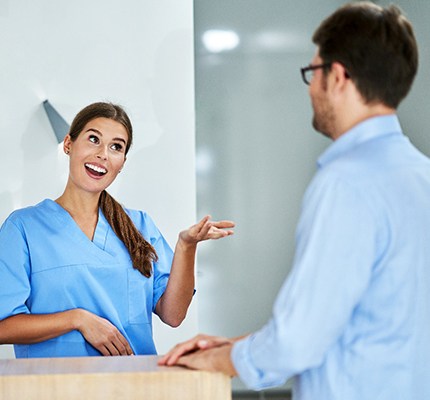 An older patient sitting next to a dental employee