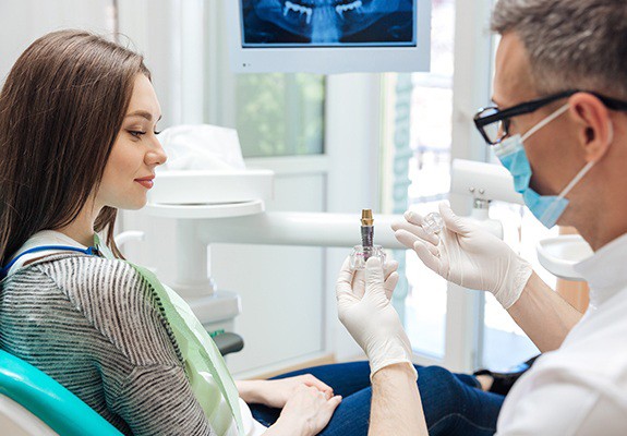A dentist showing a patient dental implant model