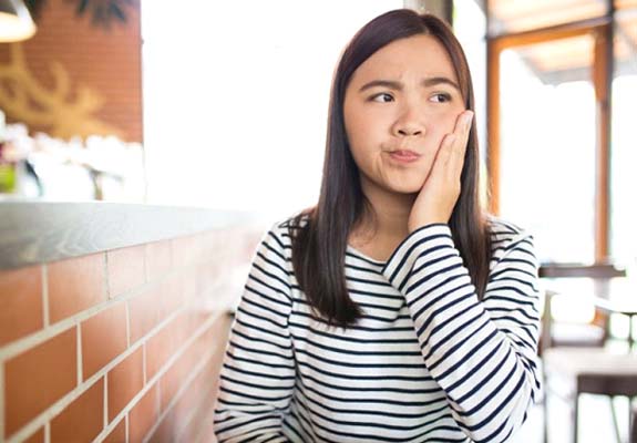 person holding their mouth in pain