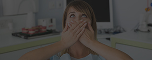 Woman in dental chair covering her mouth