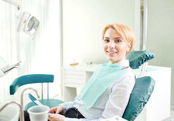 blonde woman sitting in dental chair and smiling