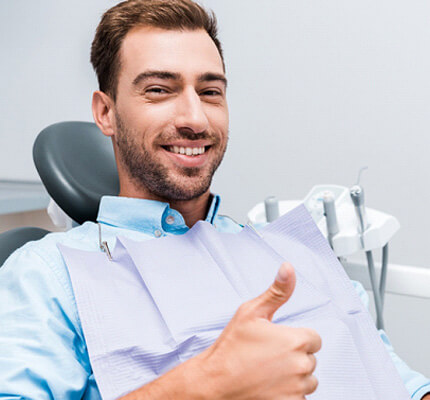 man giving a thumbs up in a dental chair