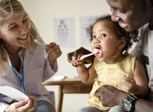 children’s dentist near Scotch Plains showing baby girl how to brush her teeth 