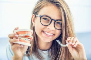 a woman holding Invisalign and traditional braces in her hands